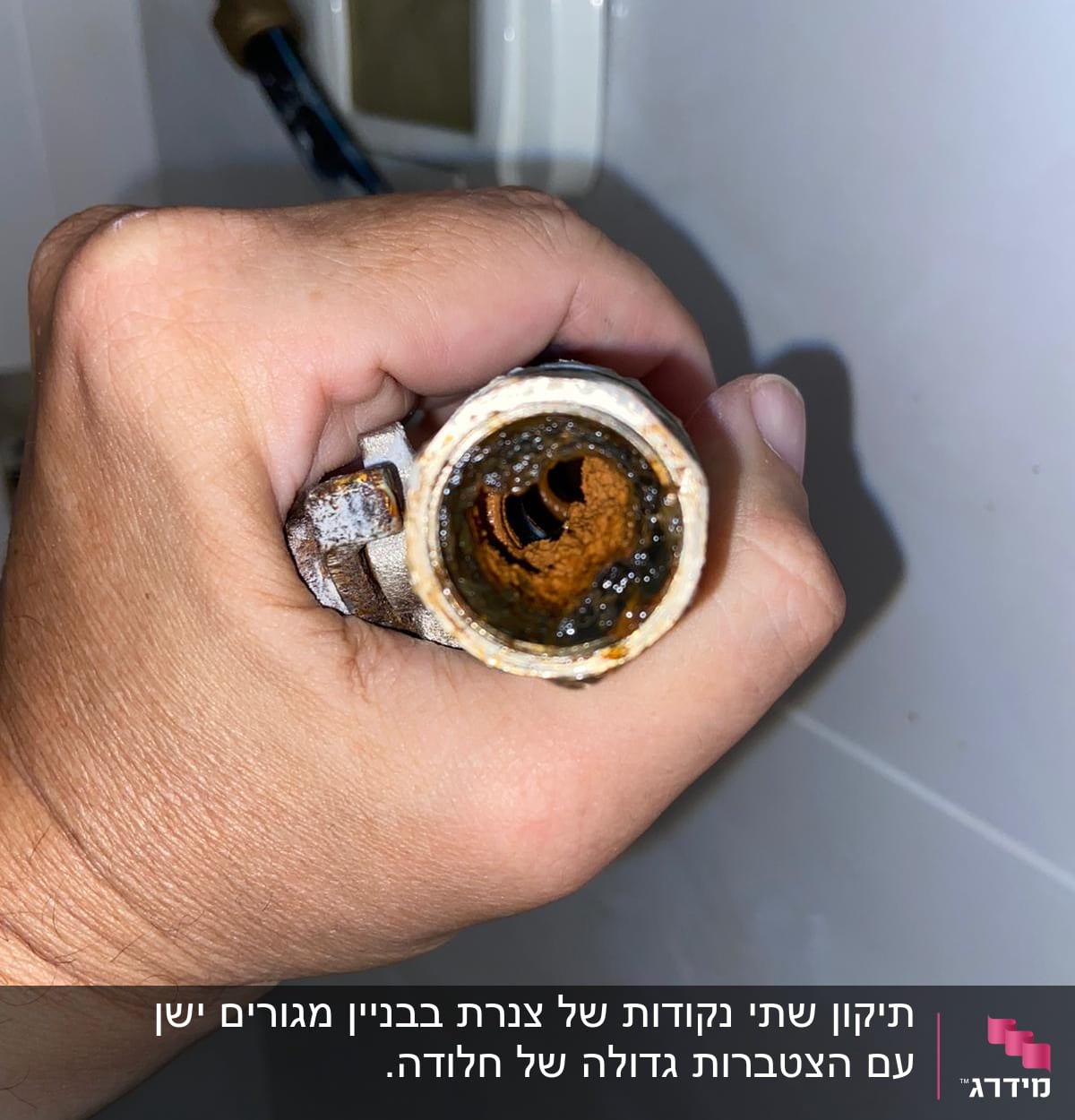 יד מחזיקה צינור חלוד עם לכלוך בפנים
